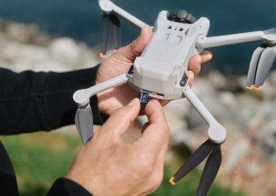 Photo d'un drone DJI mini 4 PRO dans les main du télépilote chargeant une microSD pour faire des inspections de toiture.